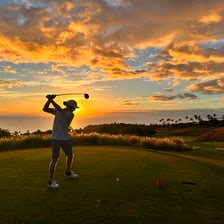 Golfer striking a ball from a tee at the start of a hole
