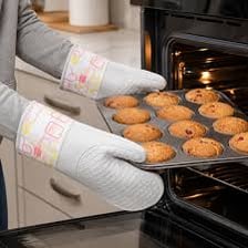 A baker using a heat-resistant mitt to hold a hot tray.