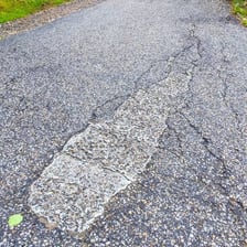 Fresh dark paving material on a roadway.
