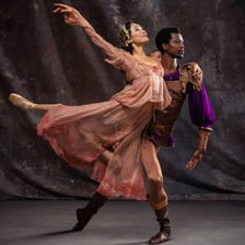 A female ballet dancer performing on a stage.