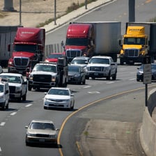 Several tractor-trailer trucks traveling on a highway