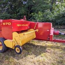 A farm hay baler producing a bale in a field