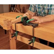 A C-shaped metal clamp holding a piece of wood.
