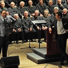 A male tenor singing with a choir.
