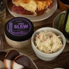 A delicatessen counter displaying prepared foods including coleslaw.