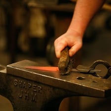 A blacksmith forging a piece of hot metal on an anvil
