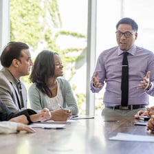 A corporate financial executive reviewing documents in a meeting.