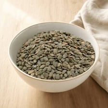 Green pumpkin seeds, also known as pepitas, in a bowl.