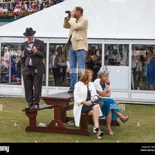 A spectator watching a horse race from beside the track rail.