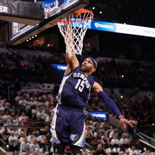 A basketball player leaping to put the ball through the hoop.