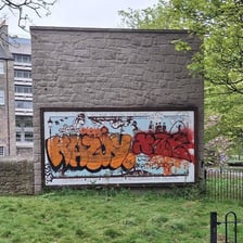 A wall marked with graffiti and other damage, showing a defaced surface.