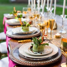 A large decorative charger plate beneath a dinner plate on a formal table.
