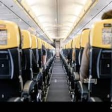 A passenger airplane cabin with a walkway between rows of seats.