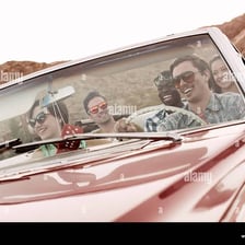 People casually driving around in a convertible car.