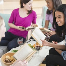 A person reading a novel during a book-club discussion