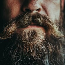 A close-up of a face with prominent unshaven whiskers.
