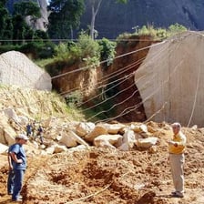 A large open quarry where workers extract stone from rock.
