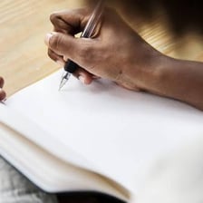 A person writing text by hand in a notebook.