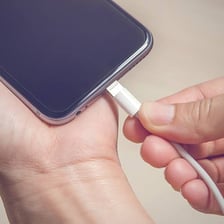 A smartphone connected to a charging cable.