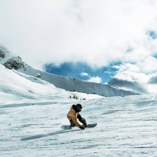 A snowboarder riding down a snow-covered slope