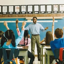 A teacher asks a student a question in a classroom.