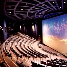 A cinema auditorium with a large IMAX screen.