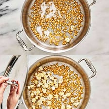 Kettle corn kernels popping in a heated pan.