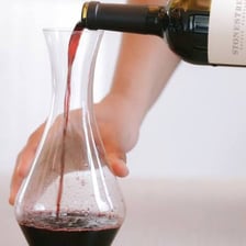 Liquid being carefully poured from one vessel into a jug.