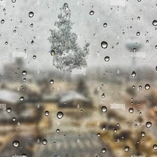Rain and snow falling from clouds over a landscape