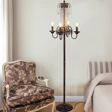 A tall antique torchère standing on the floor and holding a light