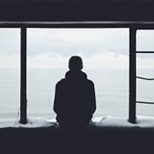 A person sits alone with a sad expression.