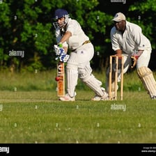 A cricket batsman playing a defensive shot to block the ball.