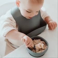 An infant wearing a bib over the chest while eating.
