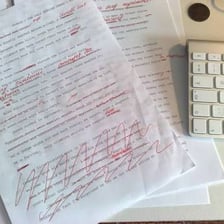 An editor marking a manuscript with strongly critical red-pen comments.