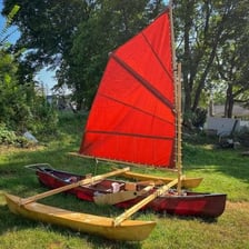 Canoe and sailboat traveling on water without visible motors