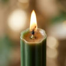 A close-up of the burning wick at the top of a taper candle.