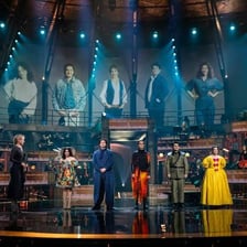 Opera singers performing a vocal aria on a stage.