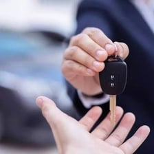 A person handing rental car keys back to a rental attendant.