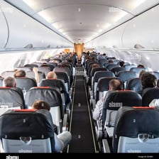 View down the aisle of an aeroplane cabin between rows of passenger seats