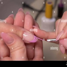 A manicurist grooming and polishing a client’s fingernails.