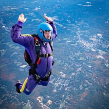 A skydiver falling through the open sky beneath a deployed parachute