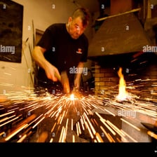 A blacksmith striking hot metal with a hammer.