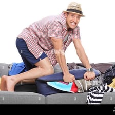 A person placing folded clothes into an open suitcase.