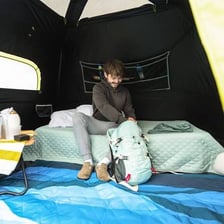 Several campers gathered inside a tent at a campsite.
