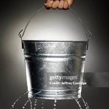 Water escaping through holes in a metal bucket