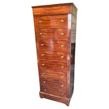 A tall antique chiffonier with multiple stacked drawers.