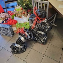 A person covering a gift with wrapping paper.