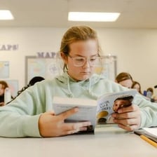 A student studying with textbooks in a classroom.