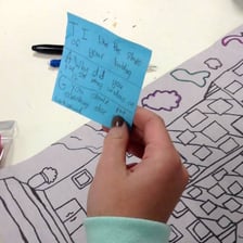 A teacher examining artwork and making detailed evaluative notes.