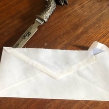 A person opening an envelope that was previously sealed.